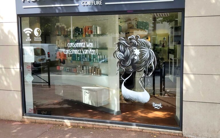 Peinture à la main sur vitrine pour un coiffeur. La peinture représente une femme de dos avec coiffure élégente style ligne claire vanves 2022