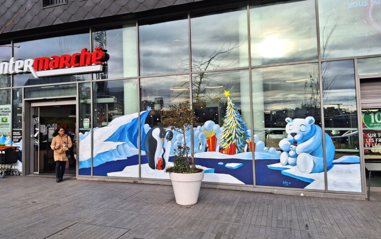 Peinture sur vitrine d'un intermarché supermarché. Fresque représentant un décors de Noel avec la banquise, sapin de Noel, pingouins et ours polaire.