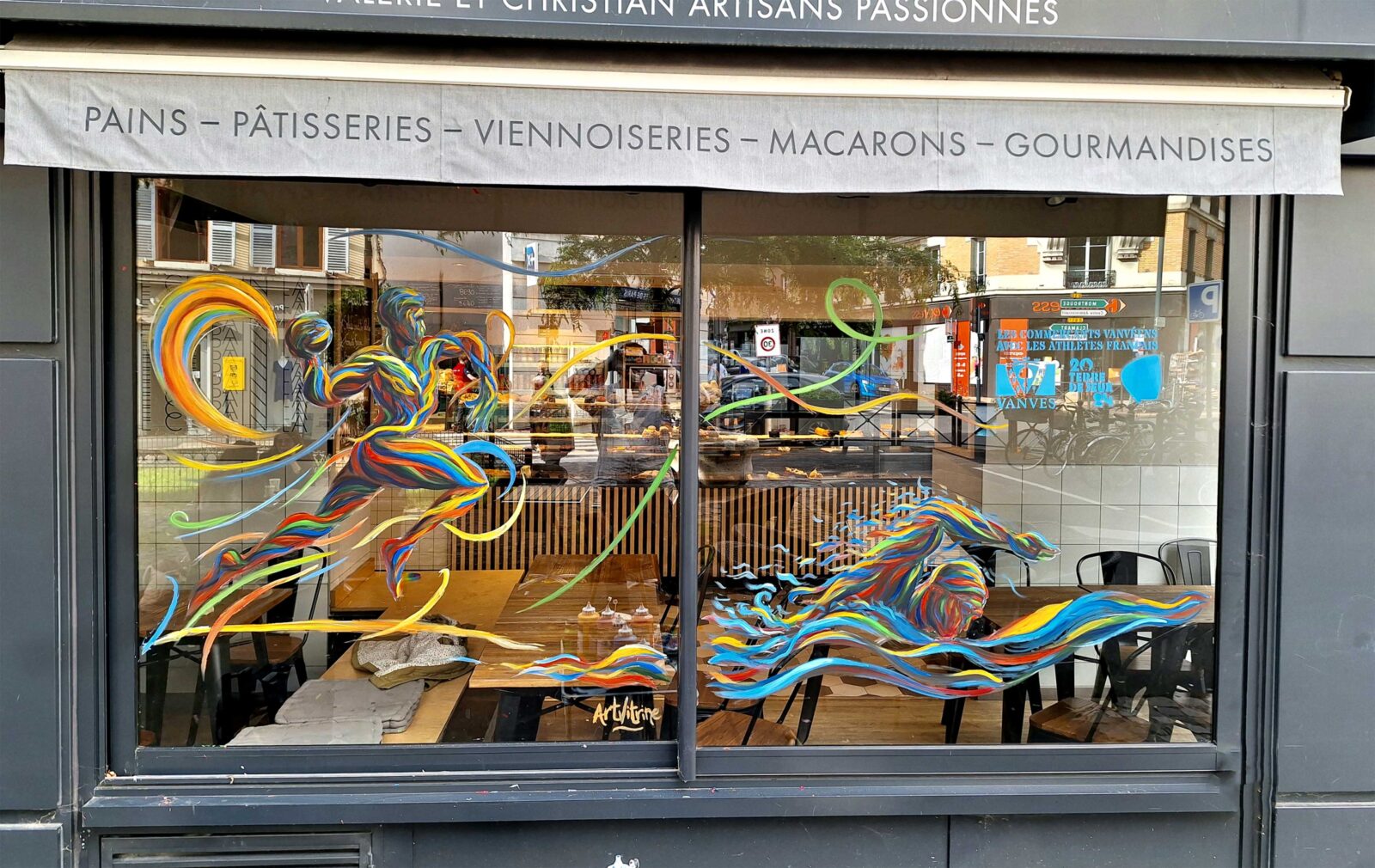 Illustration peinte sur vitrine d'un handballeur et d'un nageur aux couleurs des Jeux olympiques 2024. Les athèles sont dessinés de manière artistique pour accentuer leur mouvements. Peinte sur les toqués du pains à vanves pour les jeux olympiques 2024